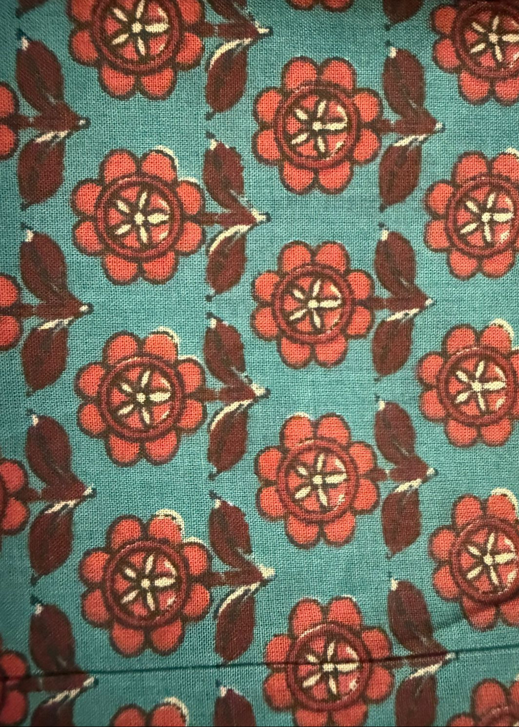 Patterned fabric with red flowers and green leaves on a blue background